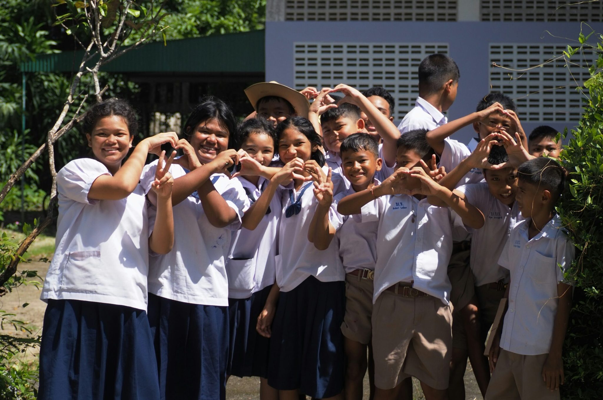 Group of students in school uniform smiling in front of their school