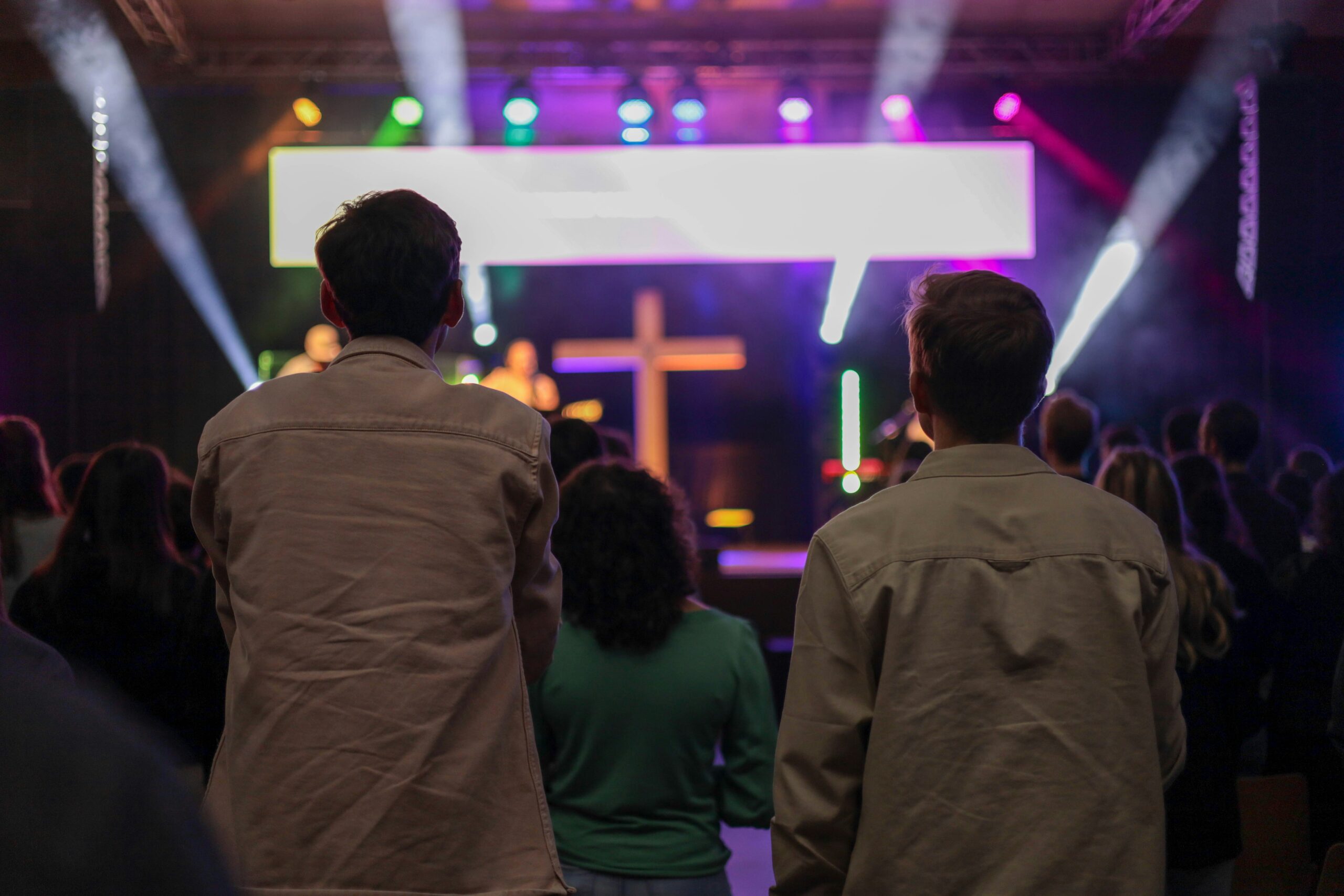 Worship gathering in front of an illuminated cross during an evangelical service